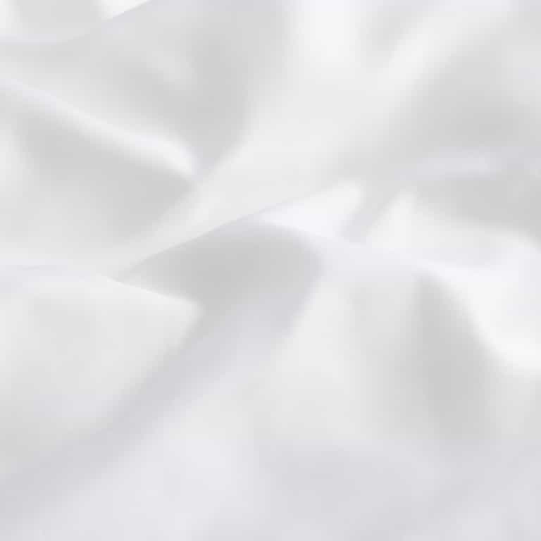 The Silk Comforter by Cozy Earth is crafted from a soft, smooth white fabric that gently folds and creases, offering a serene and clean appearance. Its evenly lit surface accentuates the texture and contours of the material.|Filling:Standard
