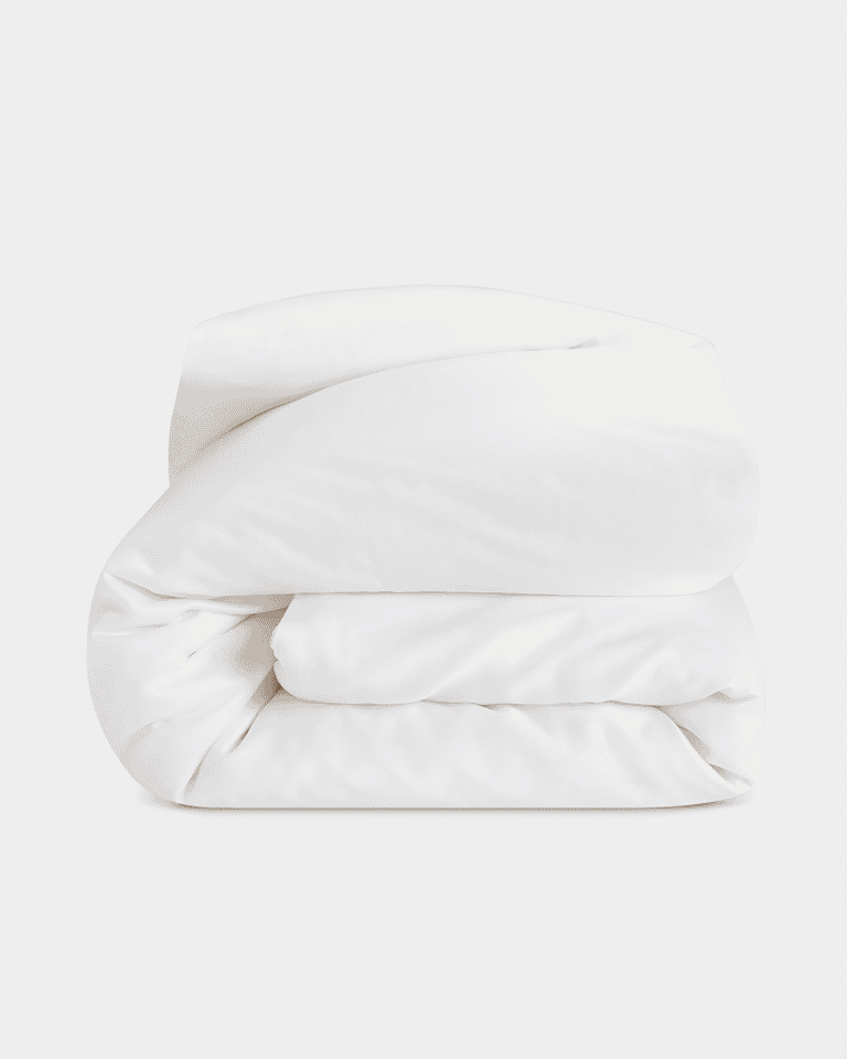 A neatly folded, fluffy Silk Comforter by Cozy Earth is placed against a plain light background. The fabric appears smooth and soft, highlighting its plush and inviting texture.|Filling:Extra