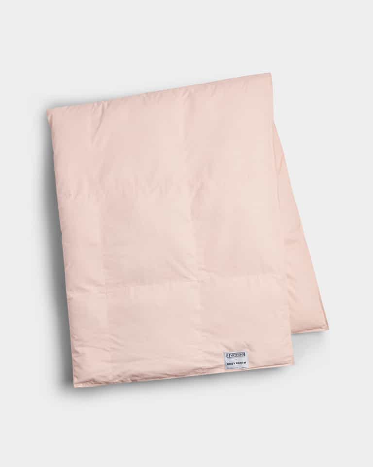 The Cozy Earth Down Alternative Throw, shown folded in light pink with a small white label near the edge, is displayed on a plain white background.|Color:Petal