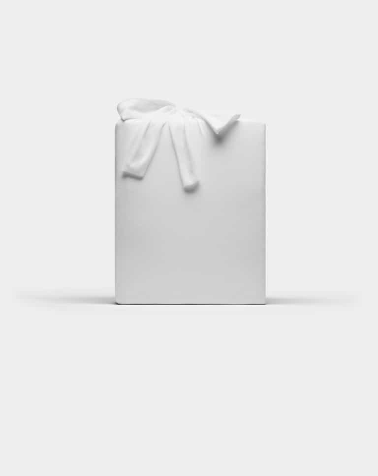 A Bamboo Jersey Sheet Set by Cozy Earth, wrapped in plain white paper with a white fabric bow on top, set against a plain white background.|Color:White