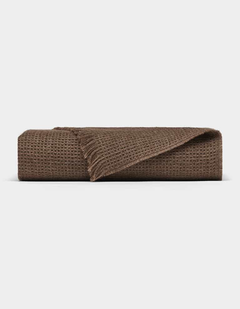 The Cozy Earth Alpaca Waffle Throw features a brown textured waffle weave and fringed edges, shown folded against a plain white background.|Color:Ebony