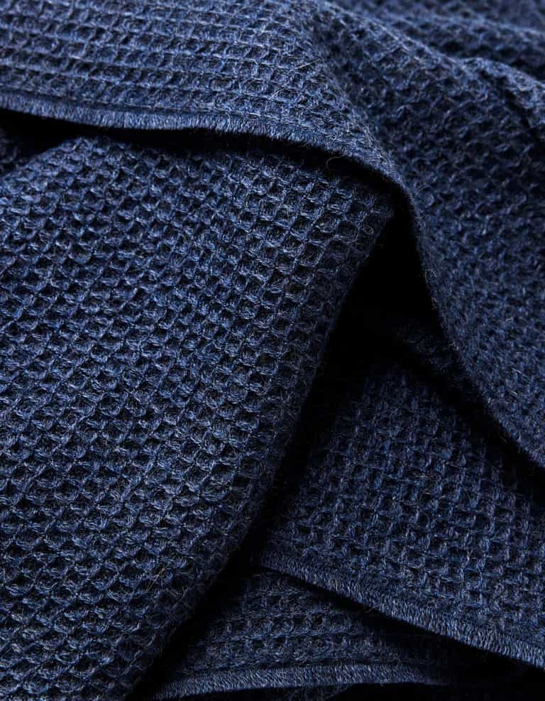 Close-up of the Cozy Earth Alpaca Waffle Throw in dark blue, showing its waffle-textured fabric with overlapping folds that emphasize the raised grid pattern and soft appearance.|Color:Slate Blue