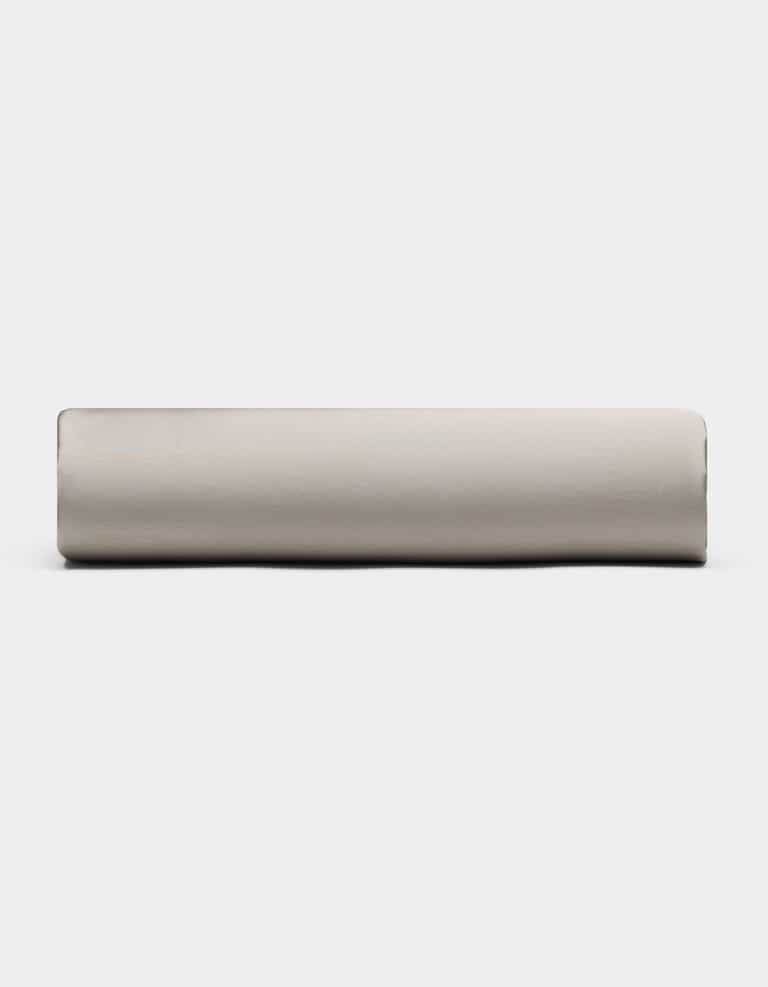 A Bamboo Fitted Sheet by Cozy Earth, in light gray, is rolled up and placed horizontally against a plain white background, viewed from the side.|Color:Dove Grey