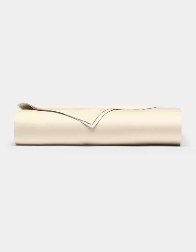 The Cozy Earth Bamboo Flat Sheet, in a light beige color, is neatly folded and displayed against a plain, light gray background.|Color:Creme