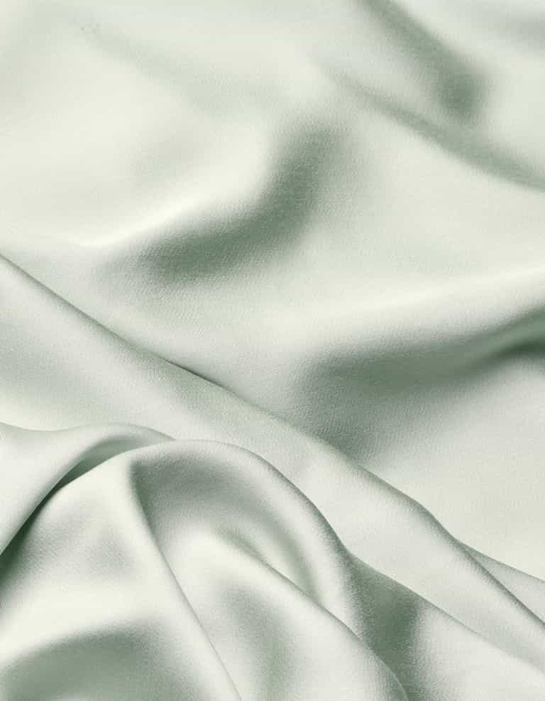 The Cozy Earth Bamboo Flat Sheet features a soft, light sage green fabric with a smooth texture and gentle folds that create subtle shadows and highlights across its surface.|Color:Laurel