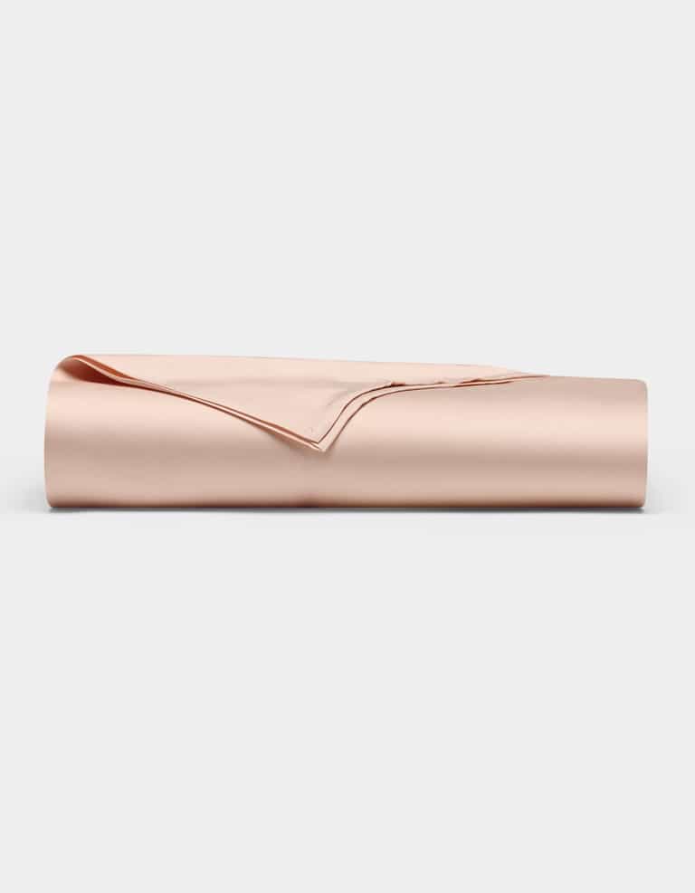 The Bamboo Flat Sheet by Cozy Earth, shown neatly folded in a light beige satin finish, is displayed against a plain white background.|Color:Peony