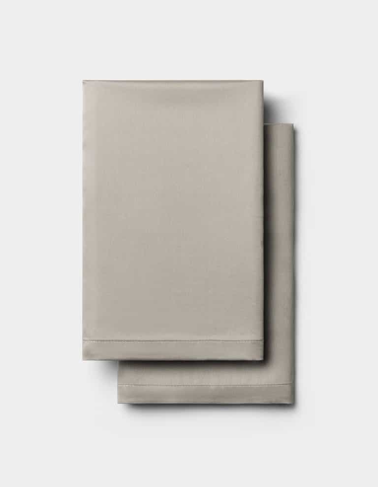 Two neatly folded Cozy Earth Bamboo Pillowcases in light gray are stacked on top of each other against a plain white background.|Color:Dove Grey
