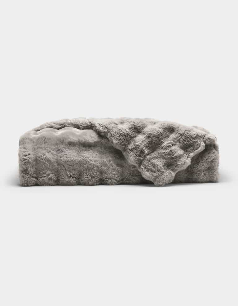 The Bubble Cuddle Blanket by Cozy Earth is a plush, light gray faux fur throw with a soft, textured surface, shown folded and partially draped open against a plain white background.|Color:Light Grey