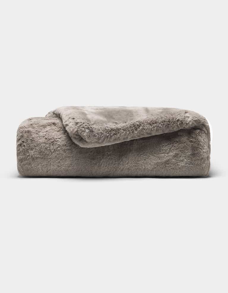 The Cozy Earth Cuddle Blanket, a soft gray faux fur throw, is neatly folded against a plain white background.|Color:Dove Grey