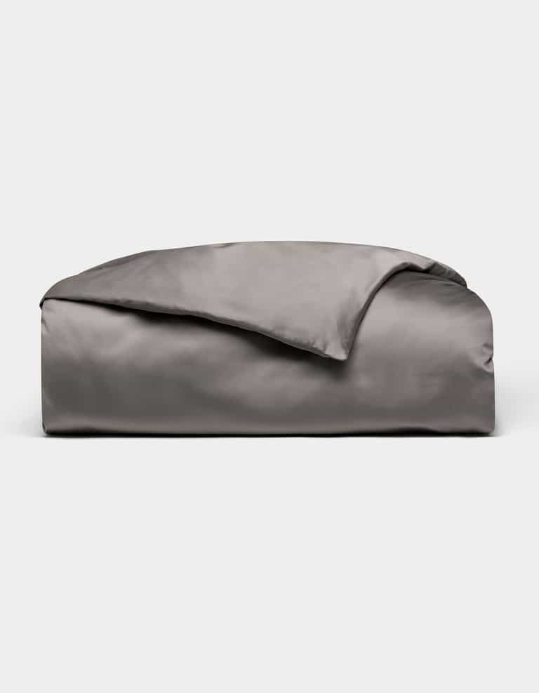 A neatly folded, shiny gray Bamboo Duvet Cover by Cozy Earth is displayed on a plain white background.|Color:Charcoal