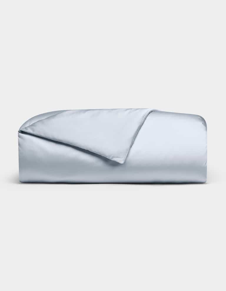 The Cozy Earth Bamboo Duvet Cover in light blue is neatly folded against a white background, with one corner flipped to reveal its smooth, silky texture.|Color:Shore