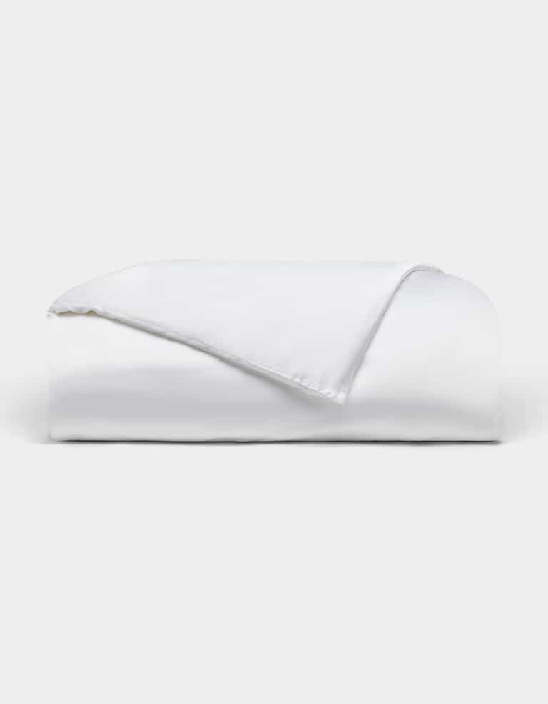 The Bamboo Duvet Cover by Cozy Earth is neatly folded with one corner flipped over, showcased against a plain light background.|Color:White