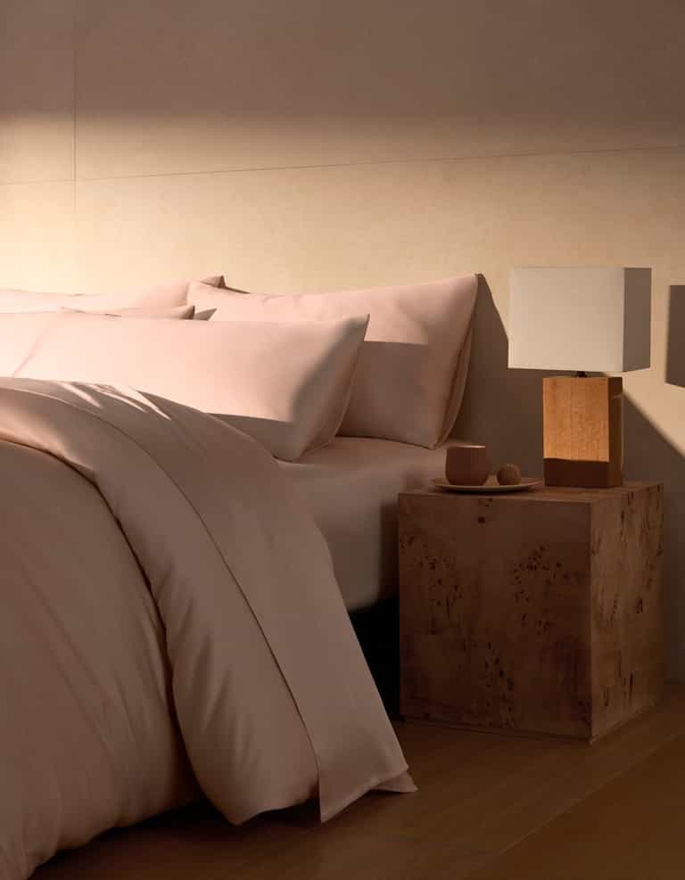 A Bamboo Duvet Cover by Cozy Earth in peony covers a cozy bed with pillows. |Color:Peony