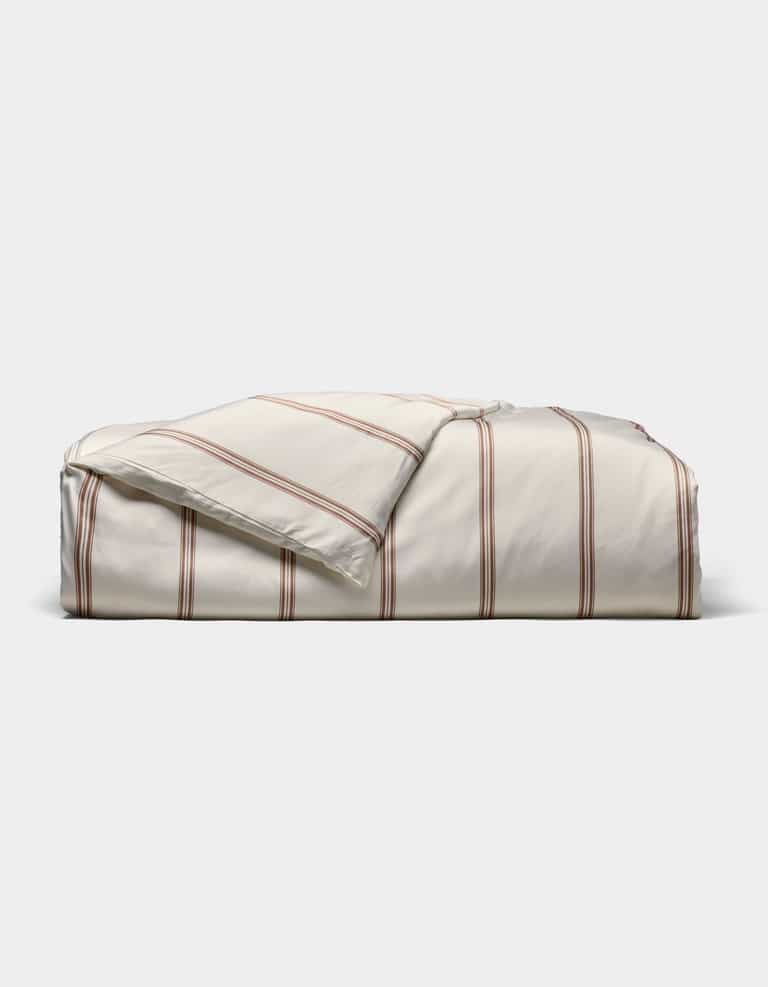 The Cozy Earth Bamboo Duvet Cover, in cream with thin red stripes, is shown neatly folded against a plain white background.|Color:Baja Stripe in Maple
