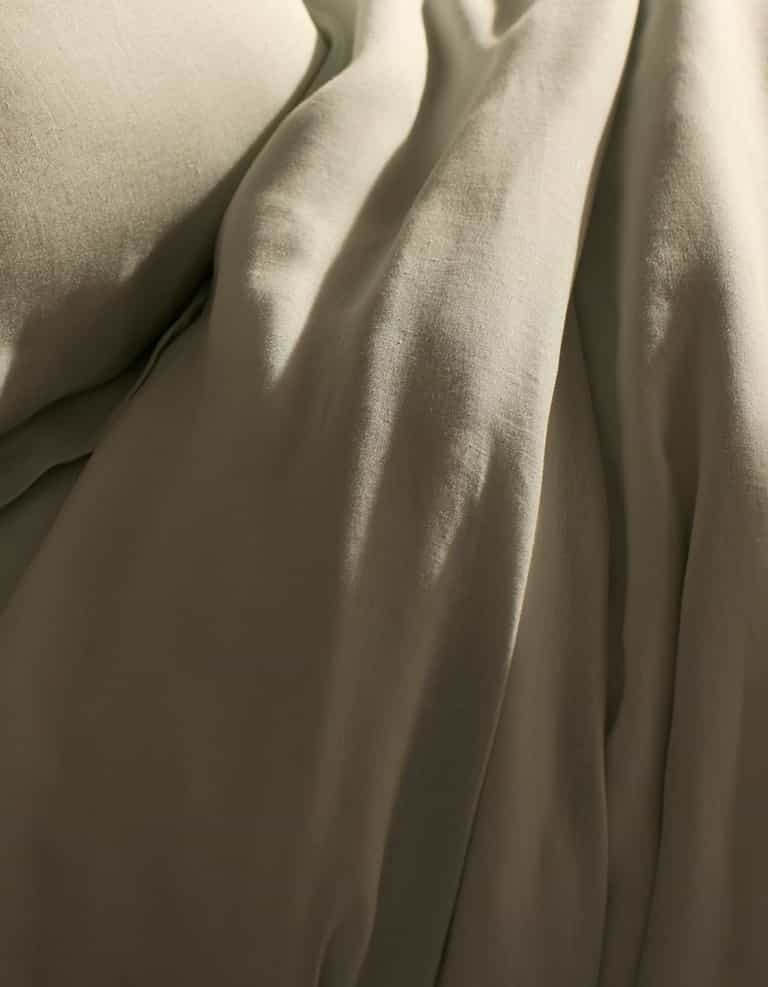 A close-up of Cozy Earth’s Linen Duvet Cover shows soft, beige fabric with gentle folds and a smooth, slightly wrinkled texture, creating a calm and cozy atmosphere—perfect for a relaxing bedroom.|Color:Mist