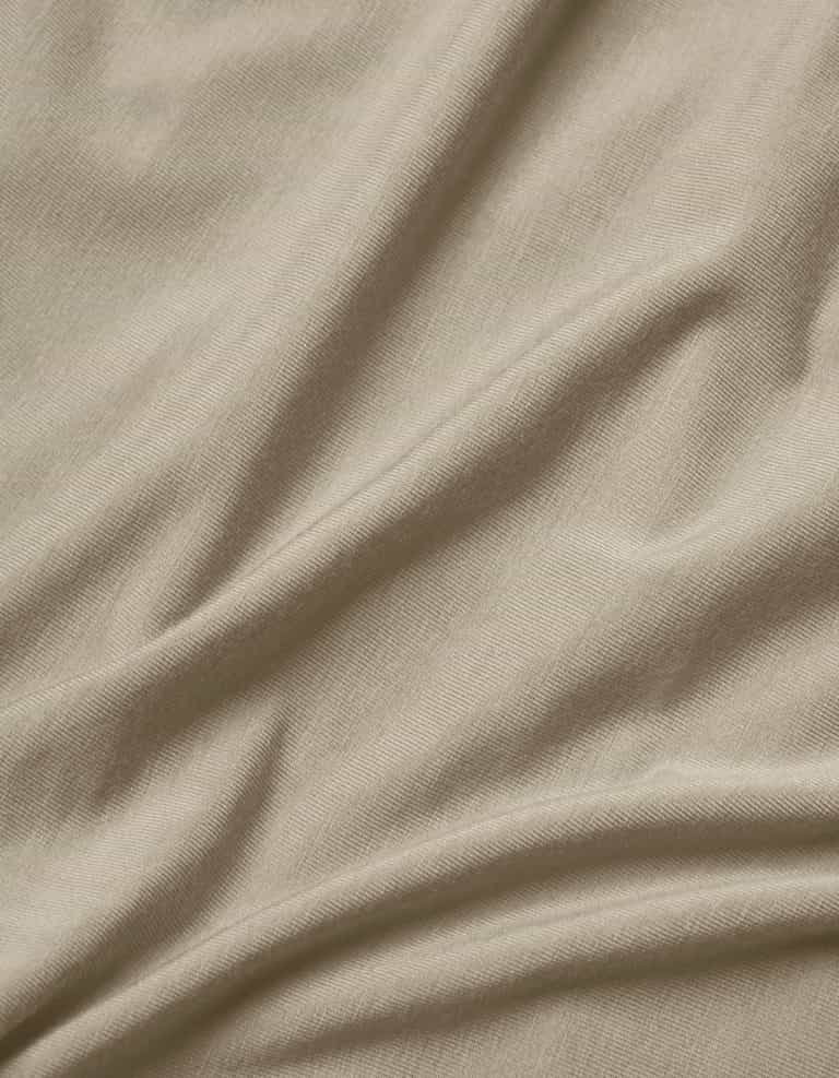 Close-up of Cozy Earth's Bamboo Jersey Flat Sheet in light beige, featuring soft, natural folds, gentle shadows, a smooth texture, and a subtle weave pattern.|Color:Driftwood
