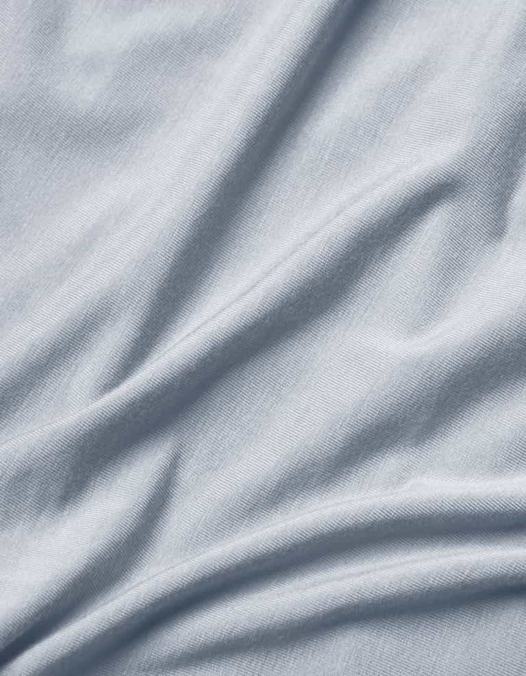 Close-up of Cozy Earth Bamboo Jersey Flat Sheet in light grey or pale blue, featuring soft folds, subtle texture, and gentle shadows and highlights.|Color:Shore