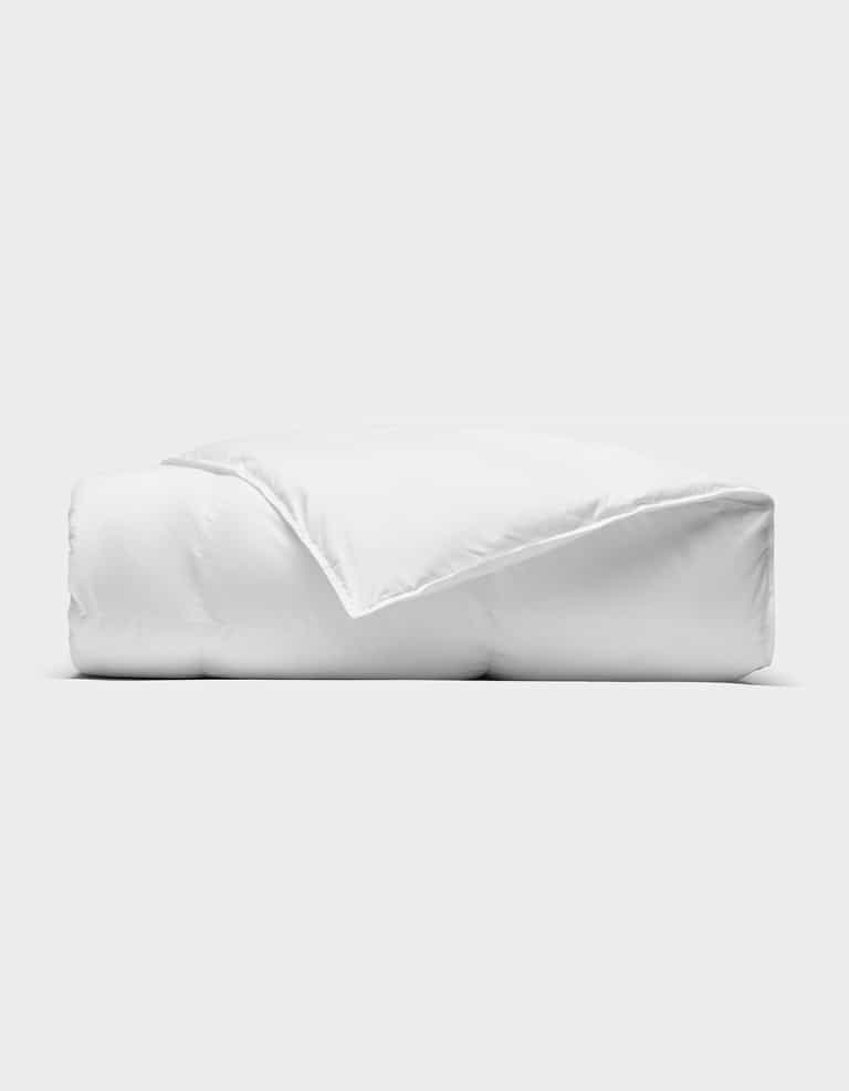 The Cozy Earth Down Alternative Throw is neatly folded against a plain, light background, with one corner turned back to reveal its soft, smooth texture.|Color:White