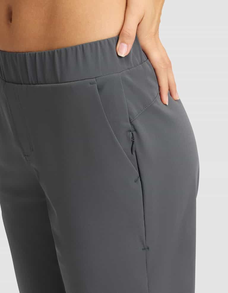 A close-up of a woman wearing Cozy Earth's Women's Always Cropped Pant in gray, featuring an elastic waistband and front pocket, with her left hand in the pocket against a plain light gray background. |Color:Coal