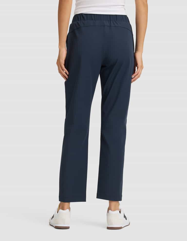 A person faces away, wearing Cozy Earth Women's Always Cropped Pant in navy blue, a white sleeveless top, and white sneakers against a plain light background. |Color:Eclipse