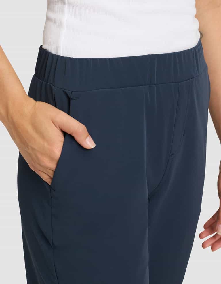 A woman wears Cozy Earth's Women's Always Cropped Pant in dark blue with a white top, placing her right hand in the pant pocket, shown from the waist down against a light background. |Color:Eclipse