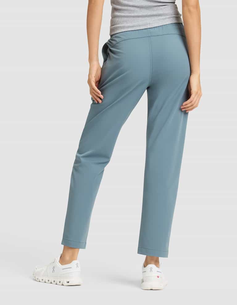 A woman, shown from the back, stands against a plain white background wearing the Cozy Earth Women's Always Cropped Pant in light blue, paired with a gray top and white sneakers. |Color:Oceanside