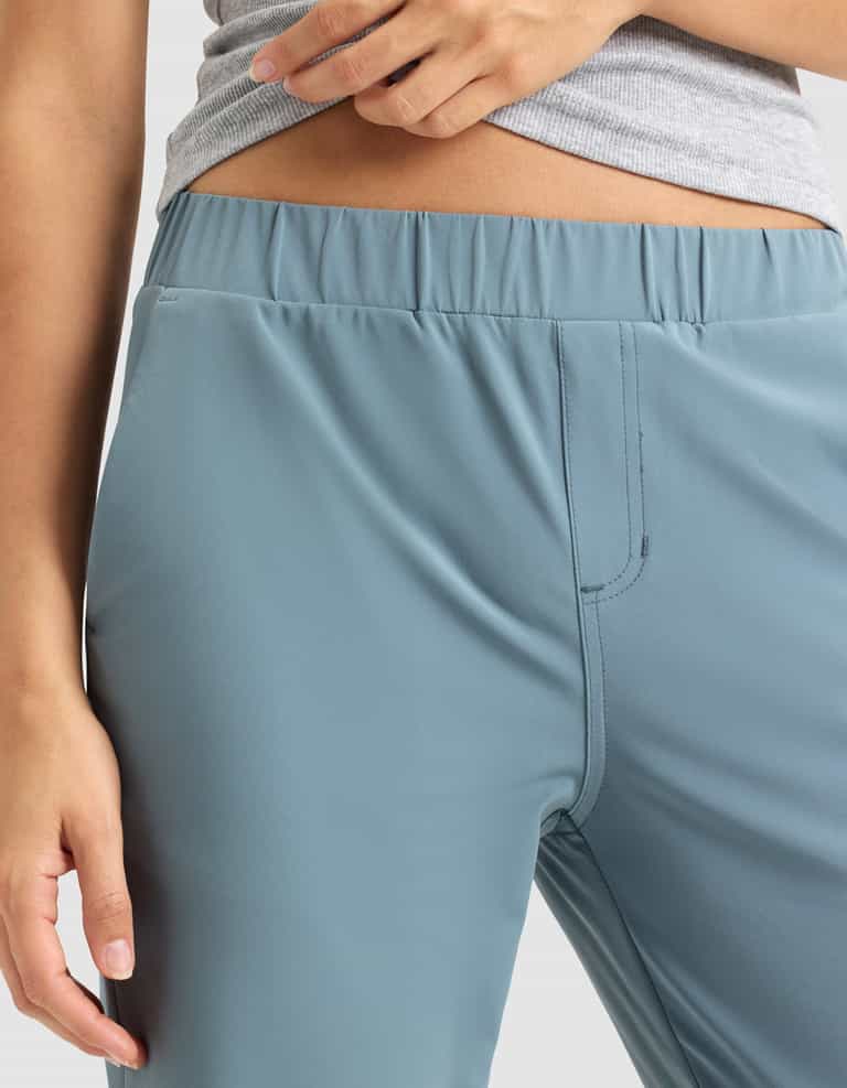 A model shows off the elastic waistband of the Cozy Earth Women's Always Cropped Pant in light blue, paired with a grey top. Only the torso and upper legs are visible. |Color:Oceanside