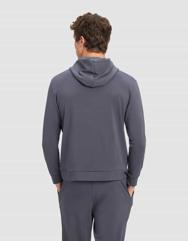 A man models the Cozy Earth Men's Brushed Bamboo Hoodie & Jogger Set in gray, standing with his back to the camera and hands in his pockets against a plain light gray background.|Color:Graphite
