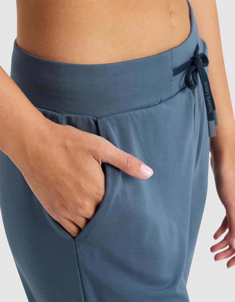 A close-up of a person wearing Cozy Earth's Women's Brushed Bamboo Jogger Pant, featuring a drawstring waist, right hand in the pocket, and showcasing the pants' soft, smooth texture.|Color:Dawn