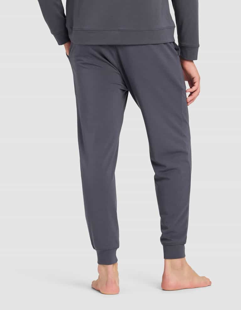 A man stands barefoot, seen from behind, wearing Cozy Earth Men's Brushed Bamboo Jogger Pant in dark gray, paired with a matching long-sleeve top, against a plain light background.|Color:Graphite