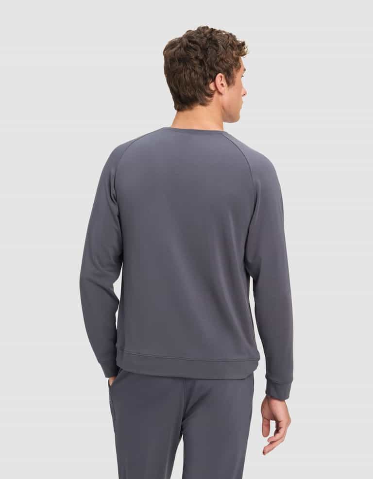 A man faces away, displaying the back of his outfit—Cozy Earth’s Men's Brushed Bamboo Pullover Crew—in gray, set against a plain light gray background.|Color:Graphite
