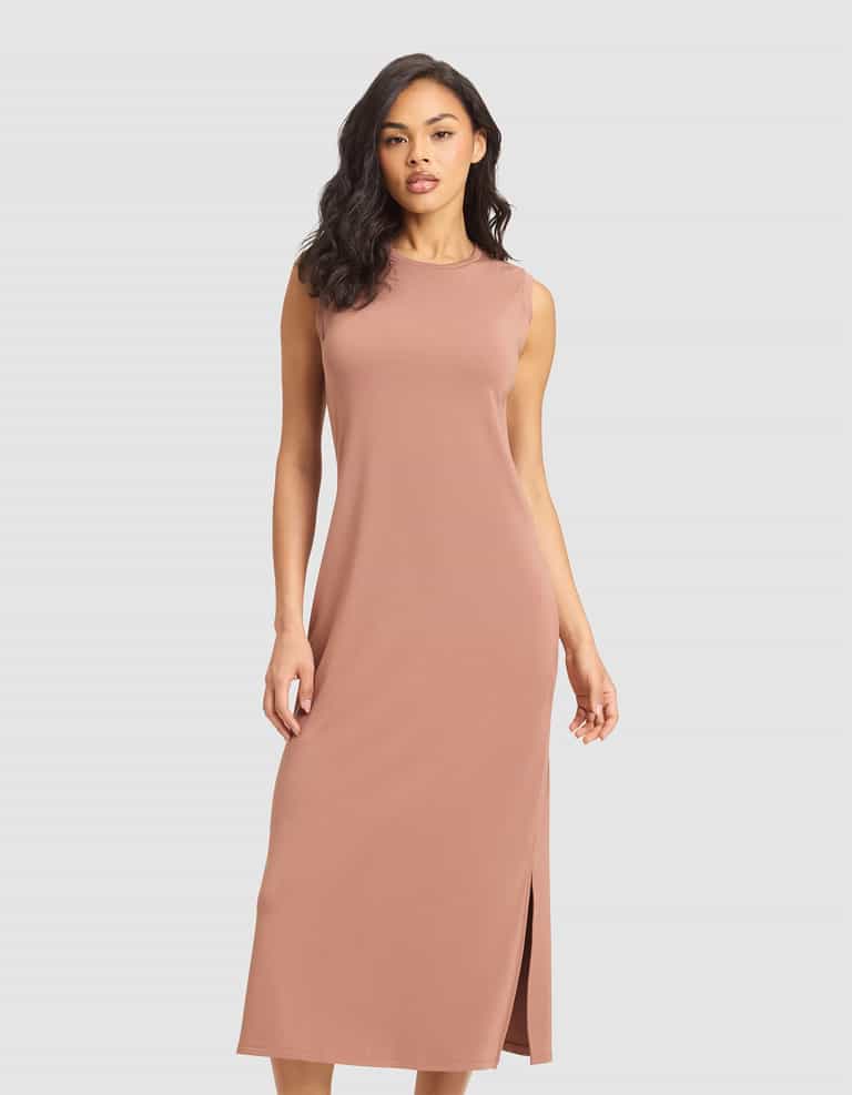 A woman models the Cozy Earth Women's Brushed Bamboo Sleeveless Midi Dress in dusty pink, featuring a side slit, against a plain light gray background. |Color:Saddle