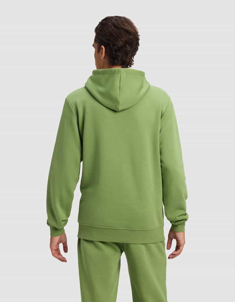 A man with short brown hair is seen from behind wearing the Cozy Earth Men's Cityscape 2.0 Hoodie in light green, paired with matching sweatpants, standing against a plain light gray background.|Color:Clover