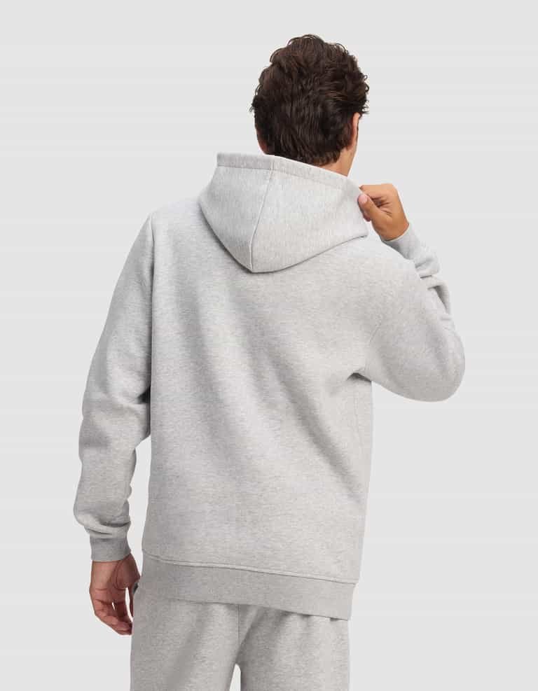 A person is seen from behind wearing the Cozy Earth Men's Cityscape 2.0 Hoodie in light gray, holding the hood against a plain, light background.|Color:Heather Grey