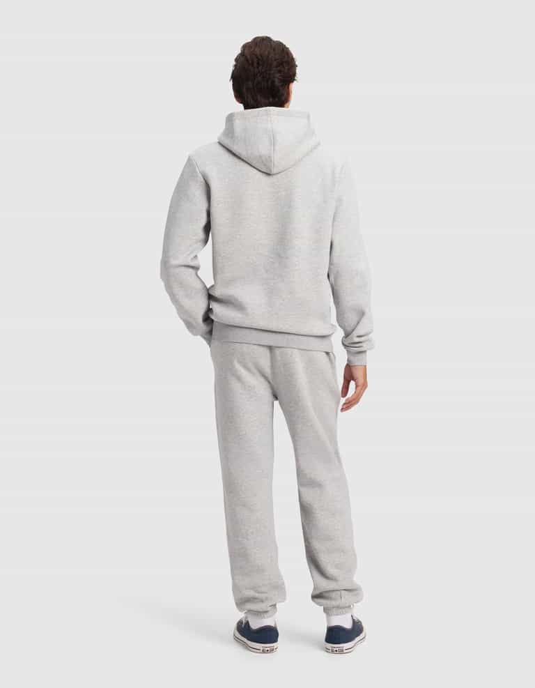 A person faces away from the camera in Cozy Earth's Men's Cityscape 2.0 Hoodie & Sweatpant Set, paired with dark sneakers, shown against a plain light background.|Color:Heather Grey