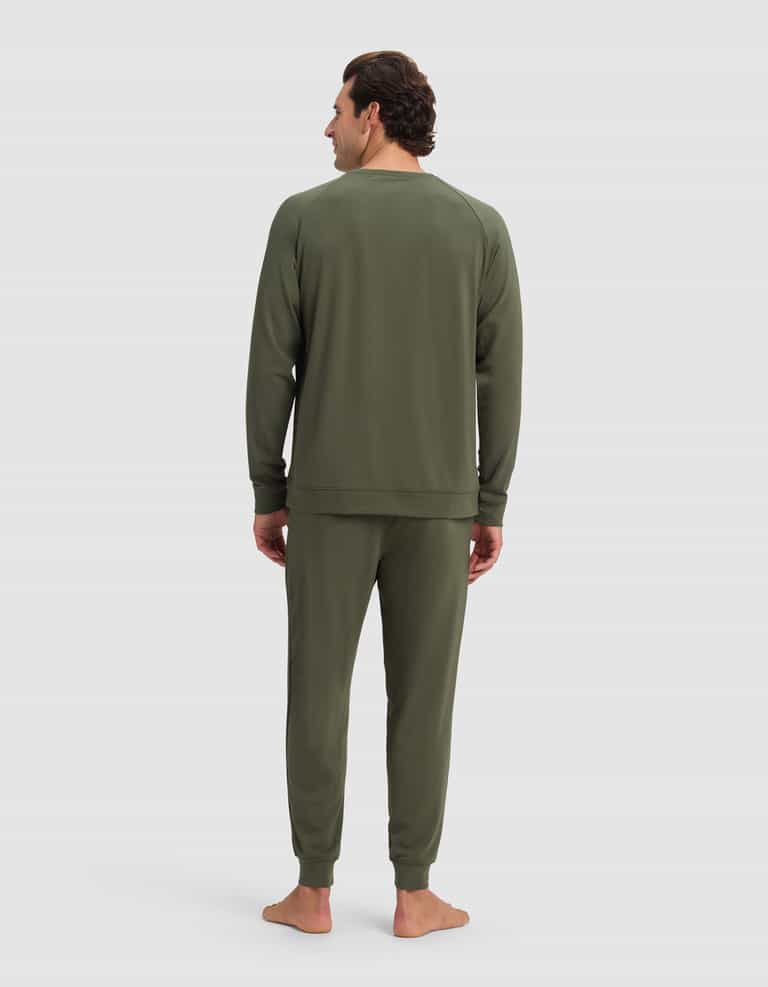 A man stands barefoot facing away, wearing the Cozy Earth Men's Brushed Bamboo Jogger Set in olive green against a plain light background.|Color:Olive