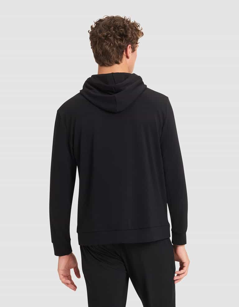 A man with curly hair is seen from behind wearing a Cozy Earth Men's Brushed Bamboo Hoodie in black, paired with black pants, set against a plain light gray background. |Color:Black