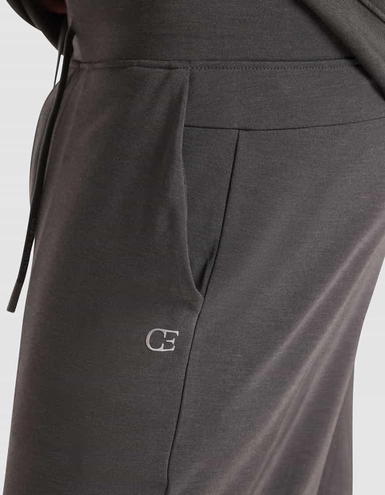 Close-up of a person wearing Cozy Earth's Men's Brushed Bamboo Jogger Pant in dark gray, featuring a visible side pocket and an embroidered white "CE" logo near the pocket. |Color:Charcoal