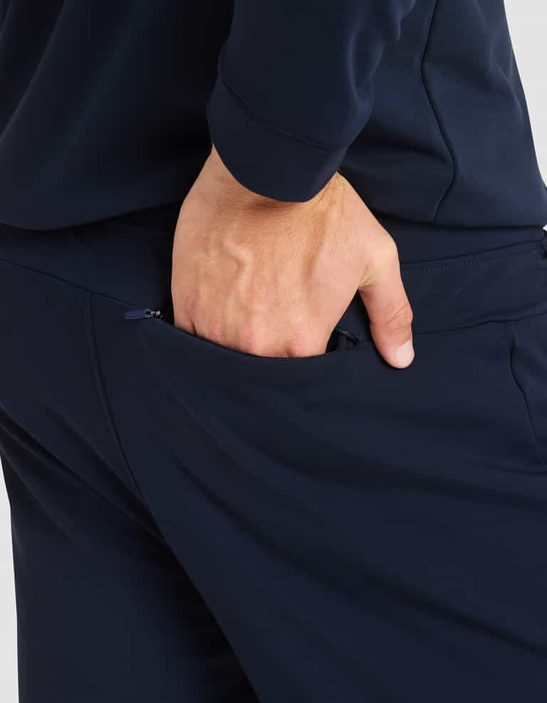 A close-up shows a person wearing Cozy Earth's Men's Brushed Bamboo Jogger Pant in navy blue, placing their right hand in the back pocket, highlighting the hand and pocket area. |Color:Navy