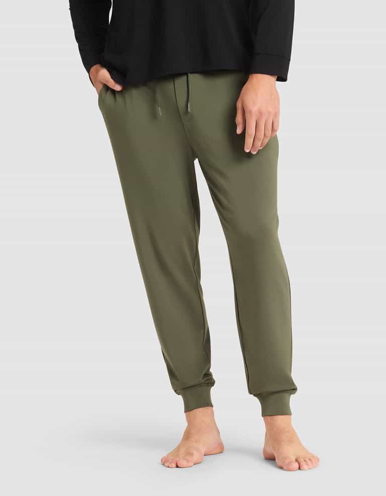 A person models the Cozy Earth Men's Brushed Bamboo Jogger Pant in olive green, shown barefoot with a black long-sleeve shirt against a plain light gray background. Only the lower half of the body is visible. |Color:Olive