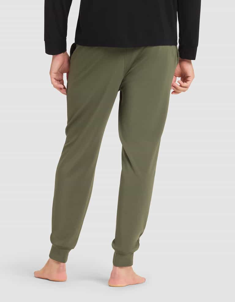 A person is standing barefoot, viewed from the back against a plain light background, wearing Cozy Earth's Men's Brushed Bamboo Jogger Pant in olive green and a black long-sleeve shirt. |Color:Olive