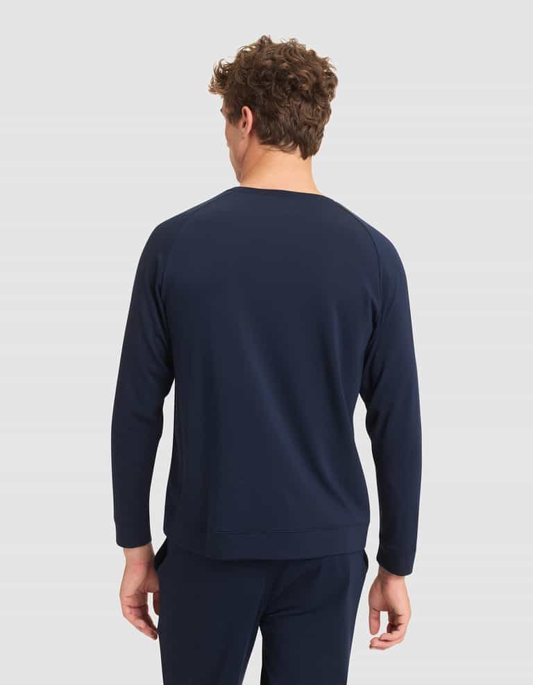 A man with curly hair is seen from behind, wearing the Cozy Earth Men's Brushed Bamboo Pullover Crew in navy blue against a plain light gray background. |Color:Navy