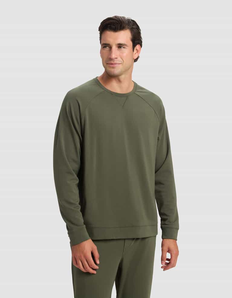 A man wearing the Cozy Earth Men's Brushed Bamboo Pullover Crew in olive green stands against a light gray background, looking slightly to his left with a neutral expression.|Color:Olive