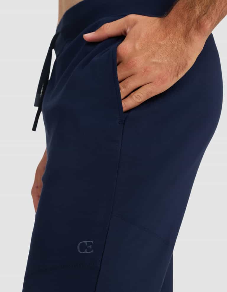 A person wearing Cozy Earth Men's Brushed Bamboo Recovery Jogger in navy blue, with one hand in the pocket, highlights the side detail and a small "CE" logo near the pocket.|Color:Navy