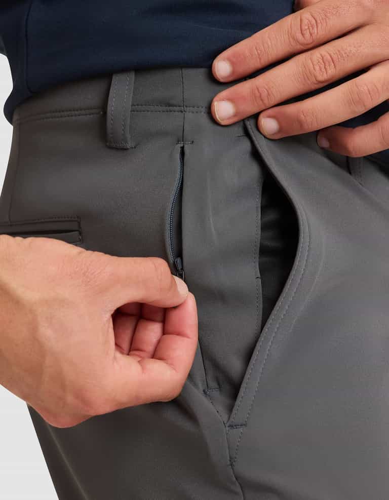 A close-up shows a person using their left hand to unzip the hidden zipper pocket inside the right side pocket of Cozy Earth's Men's Everywhere Pant (gray). |Color:Coal