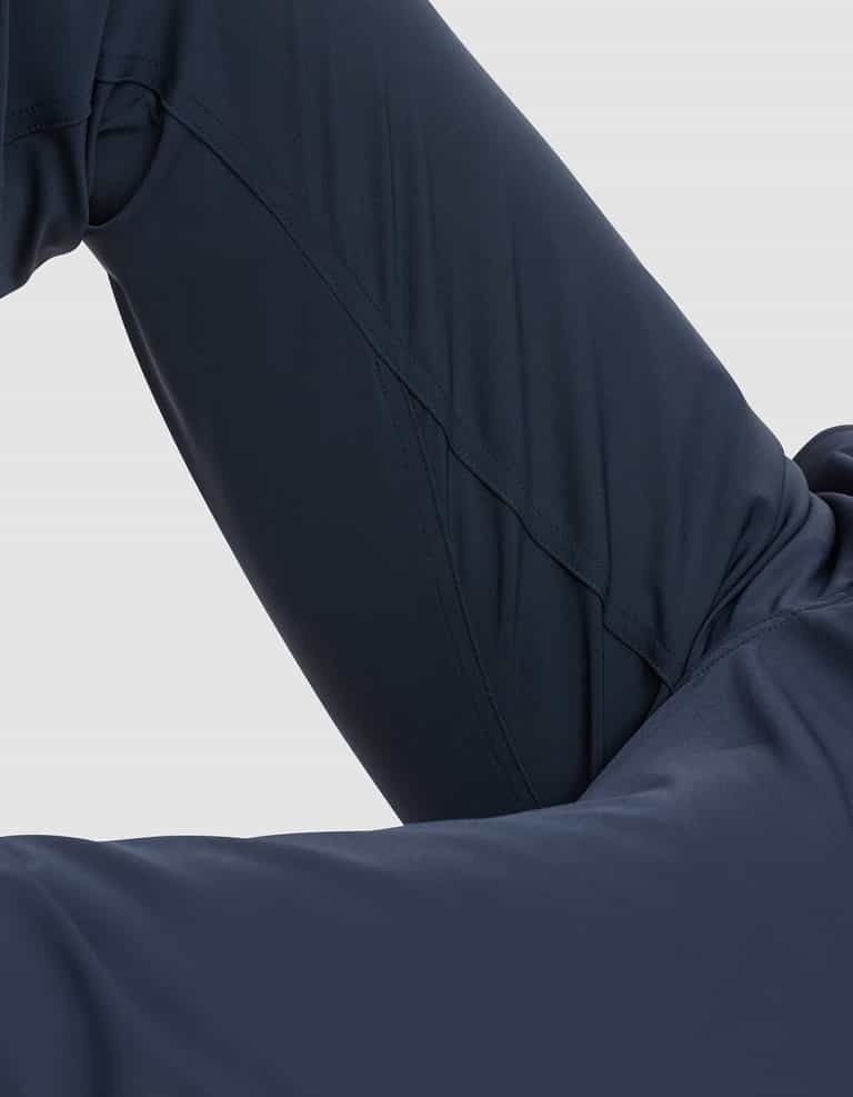 Close-up of a person wearing Cozy Earth Men's Everywhere Pant in dark navy blue, with a bent knee and leg partially visible against a light gray background. |Color:Eclipse