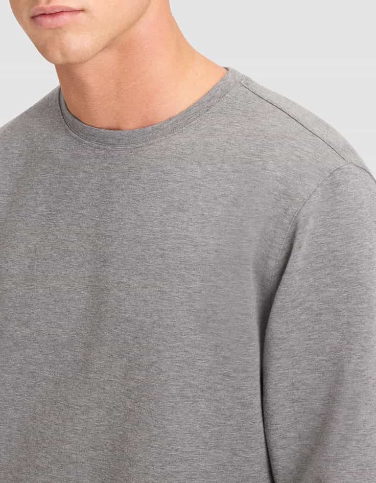 A close-up of a person wearing the Cozy Earth Men's StretchTech Crewneck & Jogger Set in grey, shown from shoulders to upper chest against a light grey background. |Color:Coal Heather