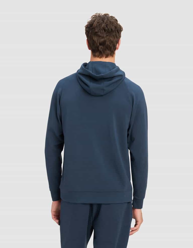 A person with curly brown hair is seen from the back, wearing the Cozy Earth Men's StretchTech Hoodie in dark blue, paired with matching pants, set against a plain light gray background.|Color:Eclipse