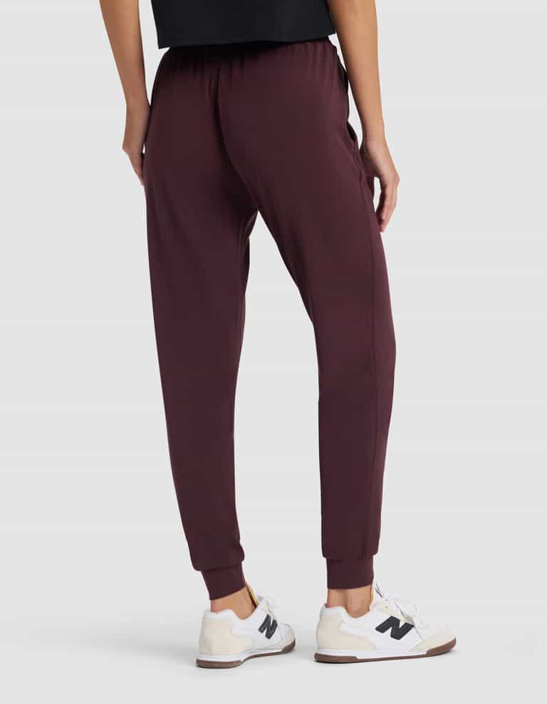 A person wearing Cozy Earth Women's Studio Jogger in burgundy and white sneakers, shown from the back with only their lower half visible against a plain light background.|Color:Raisin