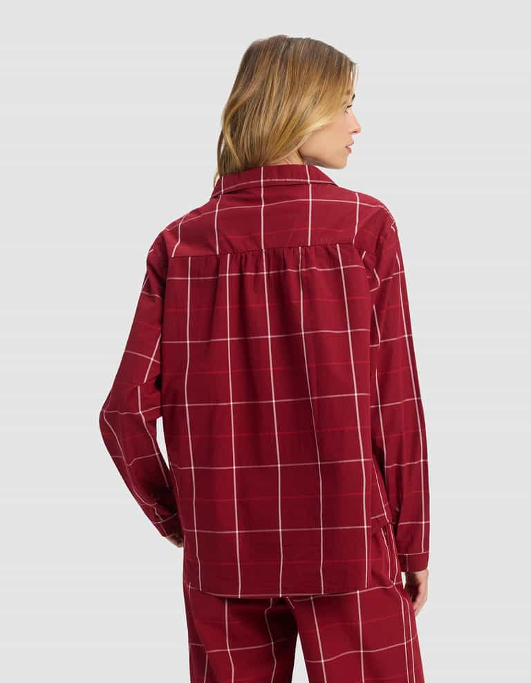 A woman with blonde hair faces away, wearing the Cozy Earth Women's Sutton Long Sleeve Pajama Set in maroon with a white checkered pattern, standing against a plain light gray background.|Color:Garnet Windowpane